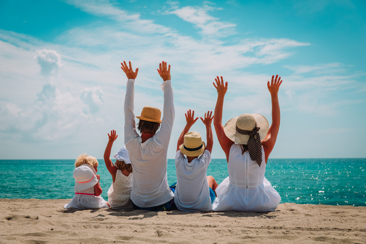 Happy family with kids hands up on beach